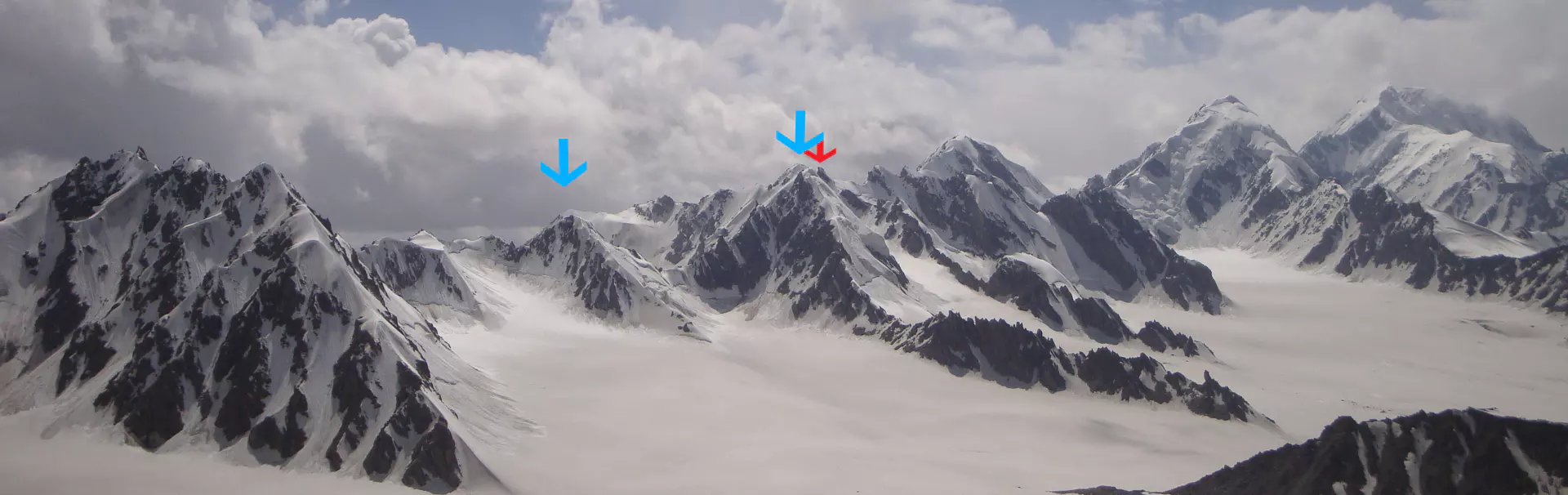 Vier bergbeklimmers met helmen en uitrusting vieren met opgeheven armen hun overwinning op de besneeuwde top van een berg. Op de voorgrond is een ijsbijl te zien, en achter hen is de hemel bedekt met 